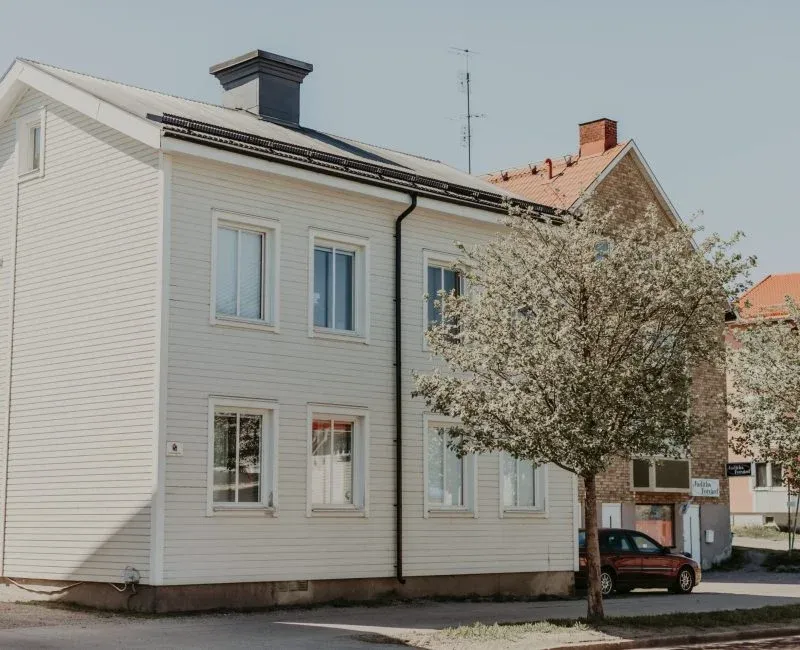 Ljust tvåvåningshus med blommande träd framför